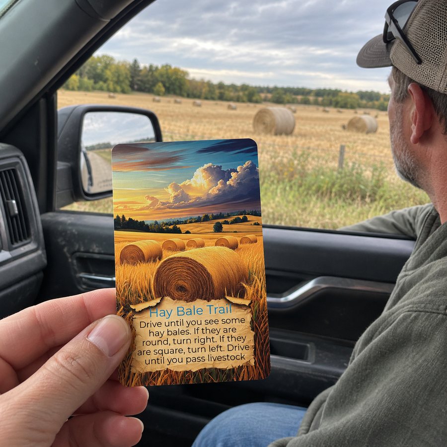 Destination Unknown card held up beside hay bales